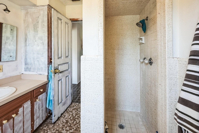 bathroom with tile walls, vanity, and tiled shower