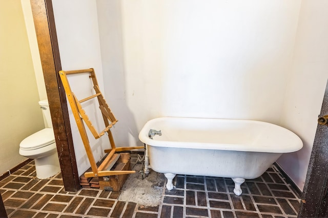 bathroom with a tub to relax in and toilet