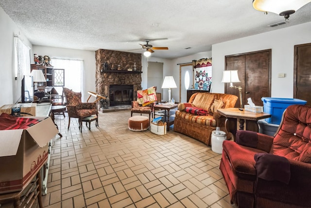 living room featuring a fireplace, a textured ceiling, and ceiling fan