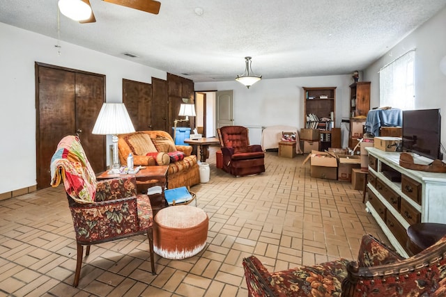 living room featuring ceiling fan and a textured ceiling