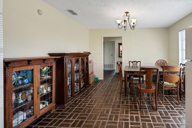 dining room with an inviting chandelier and a textured ceiling