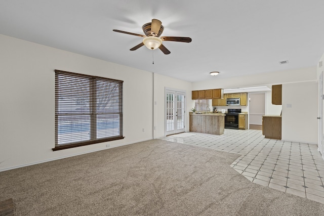 unfurnished living room with ceiling fan, plenty of natural light, french doors, and light carpet