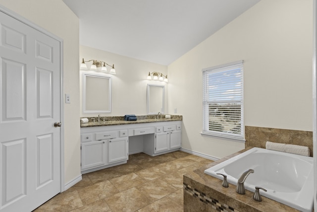 bathroom with tiled bath, vaulted ceiling, and vanity