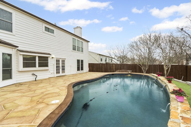 view of swimming pool with pool water feature, a patio area, and french doors