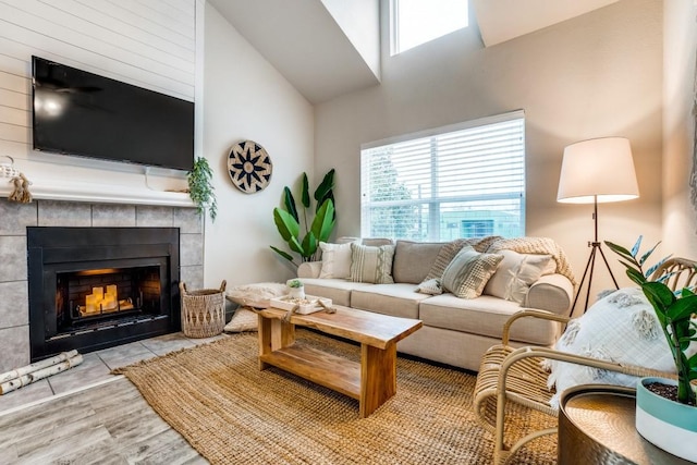 living room with a healthy amount of sunlight, a fireplace, a high ceiling, and wood finished floors