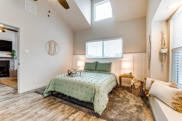 bedroom featuring a high ceiling, ceiling fan, and light hardwood / wood-style flooring