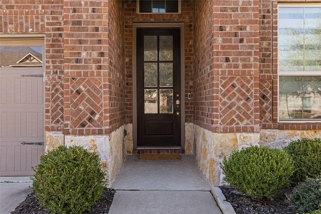 doorway to property featuring a garage and brick siding