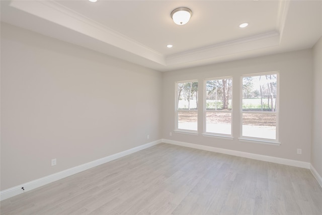 unfurnished room with crown molding, a tray ceiling, and light hardwood / wood-style floors