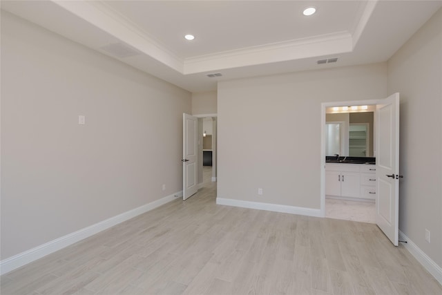 unfurnished bedroom with a raised ceiling, light wood-type flooring, and ornamental molding