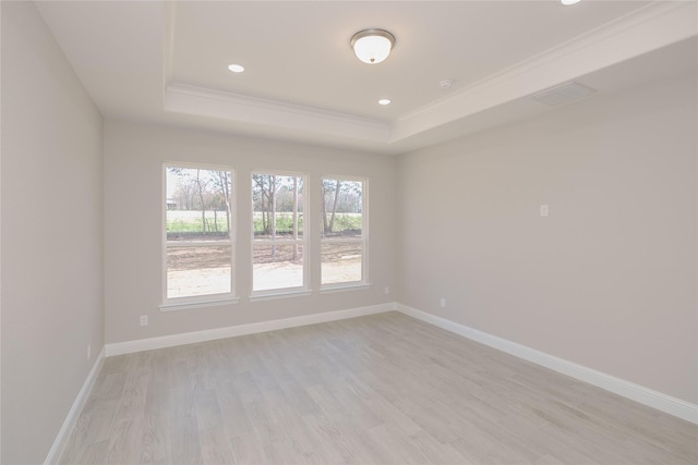 unfurnished room with a tray ceiling, light hardwood / wood-style floors, and crown molding