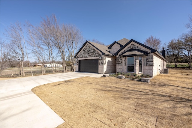 view of front of house with a front lawn, central AC unit, and a garage