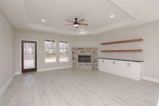 unfurnished living room with light hardwood / wood-style floors, a tray ceiling, and a fireplace