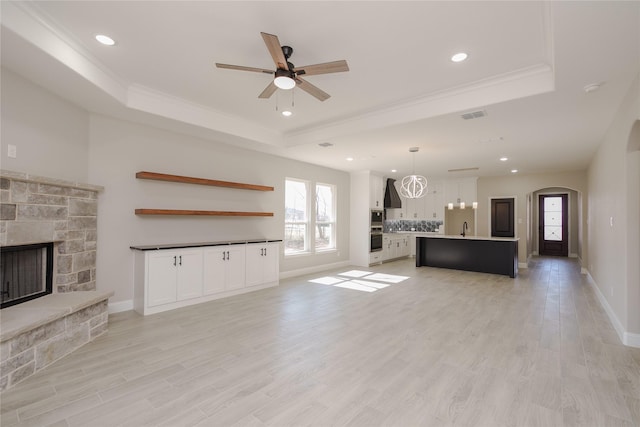 unfurnished living room with a fireplace, sink, light hardwood / wood-style floors, and a raised ceiling