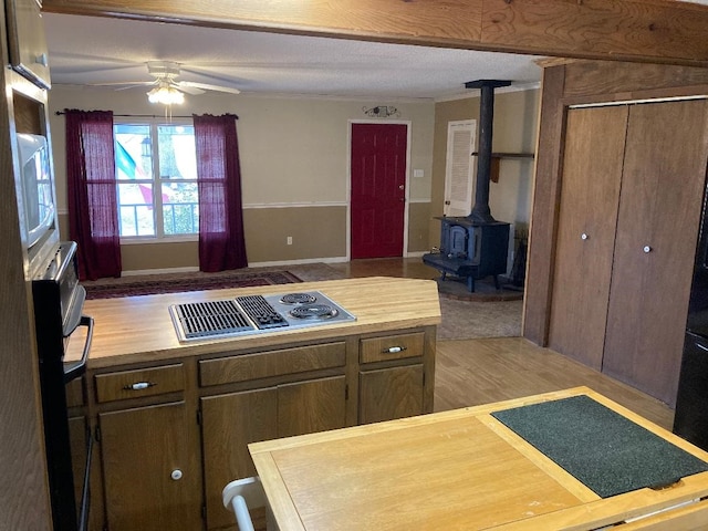 kitchen with a wood stove, light hardwood / wood-style flooring, gas stovetop, and ceiling fan