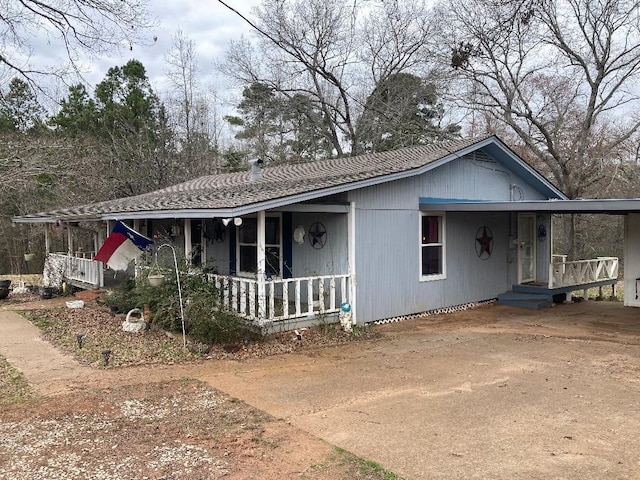 view of front facade with an attached carport, a porch, and driveway