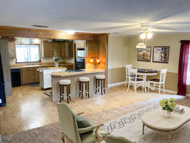 kitchen with a textured ceiling, a sink, light countertops, black appliances, and a peninsula
