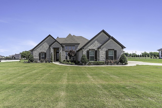 french country home with stone siding and a front lawn