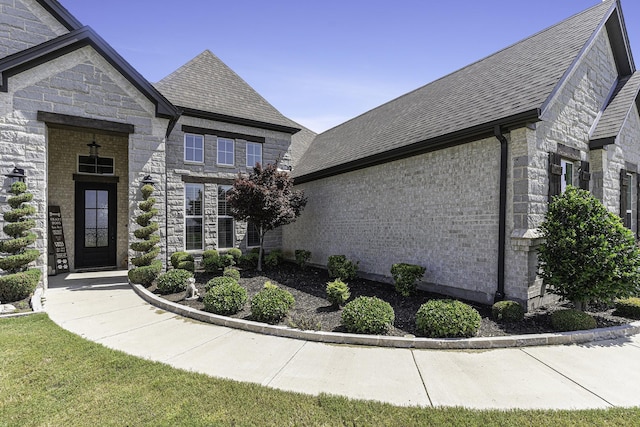 view of front of house featuring stone siding and roof with shingles