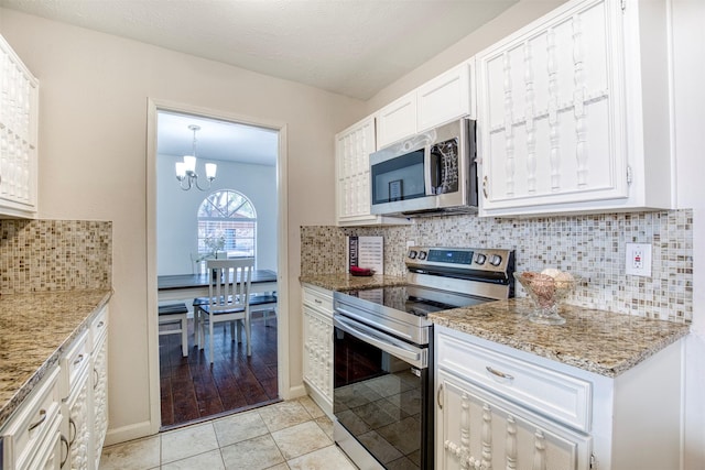 kitchen with decorative backsplash, light stone counters, stainless steel appliances, white cabinetry, and light tile patterned flooring