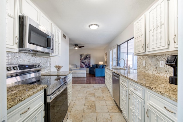 kitchen with visible vents, light stone counters, open floor plan, stainless steel appliances, and white cabinetry