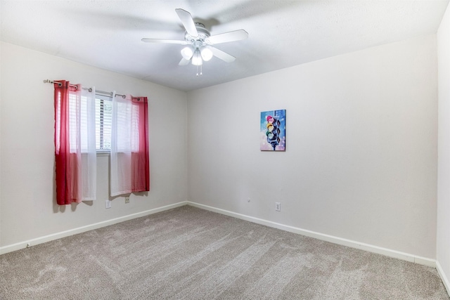 carpeted spare room featuring a ceiling fan and baseboards