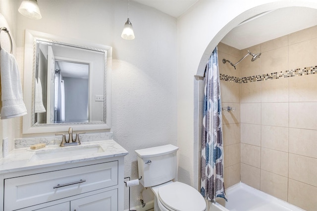 bathroom featuring toilet, a textured wall, a shower with shower curtain, and vanity