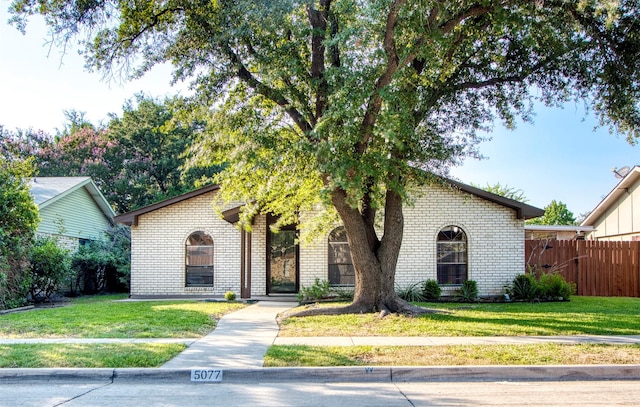 view of front of home featuring brick siding, a front yard, and fence