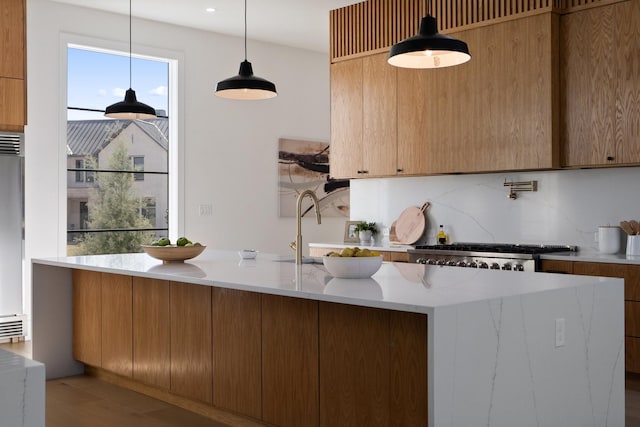 kitchen featuring light hardwood / wood-style flooring, stove, pendant lighting, backsplash, and sink