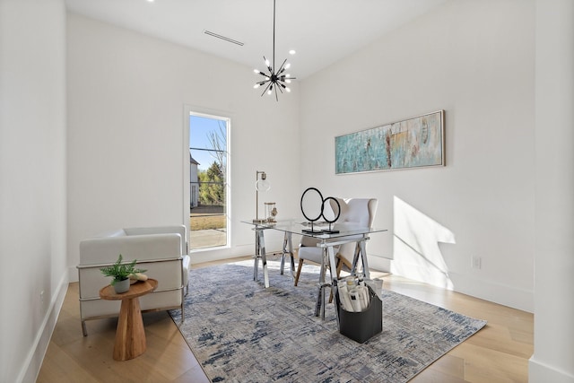 office space with an inviting chandelier and light hardwood / wood-style flooring