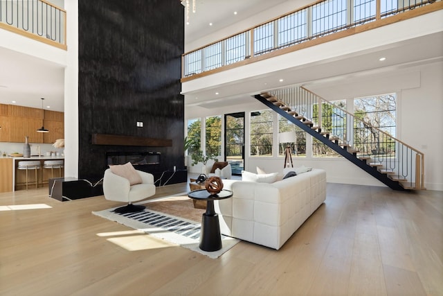 living room featuring a fireplace, a towering ceiling, and light hardwood / wood-style flooring