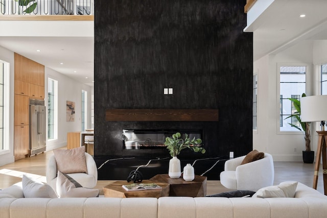 living room with a large fireplace, a towering ceiling, and light hardwood / wood-style flooring