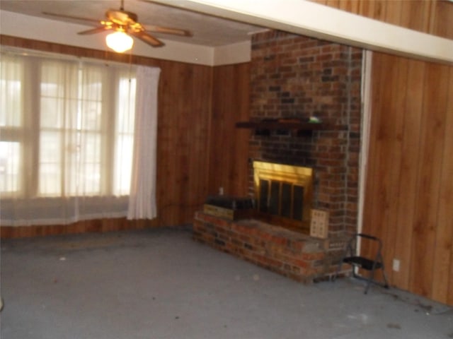 unfurnished living room with a fireplace, ceiling fan, and wooden walls