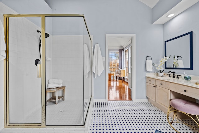 bathroom featuring lofted ceiling, a shower stall, vanity, and baseboards