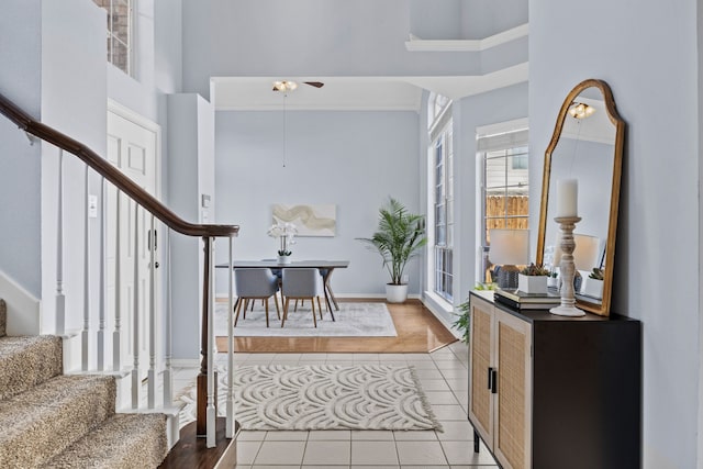 entrance foyer with a towering ceiling, light tile patterned floors, and stairs