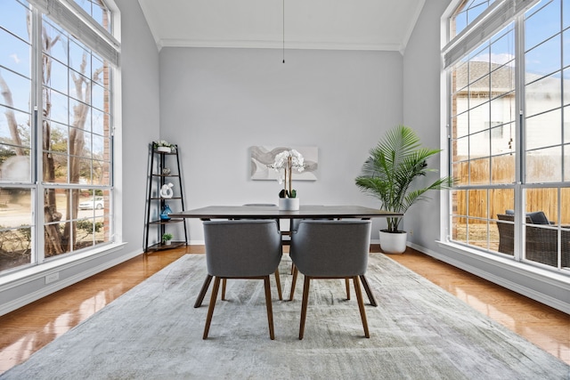 dining space with ornamental molding, light wood-type flooring, a wealth of natural light, and baseboards