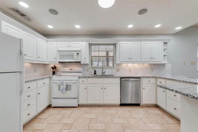 kitchen featuring white appliances, sink, white cabinets, and light stone countertops