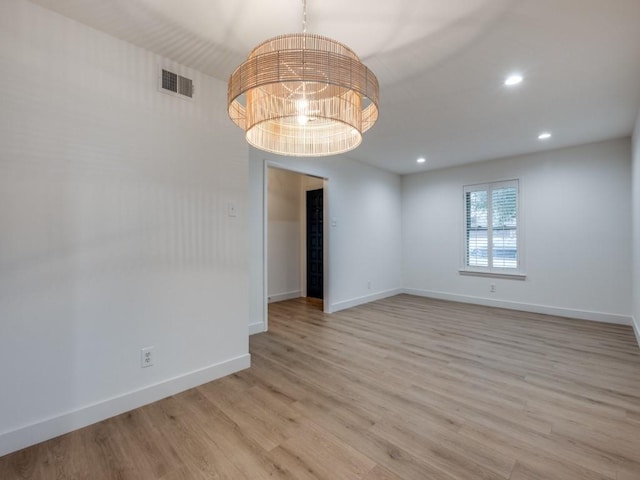 empty room featuring light hardwood / wood-style flooring and a chandelier