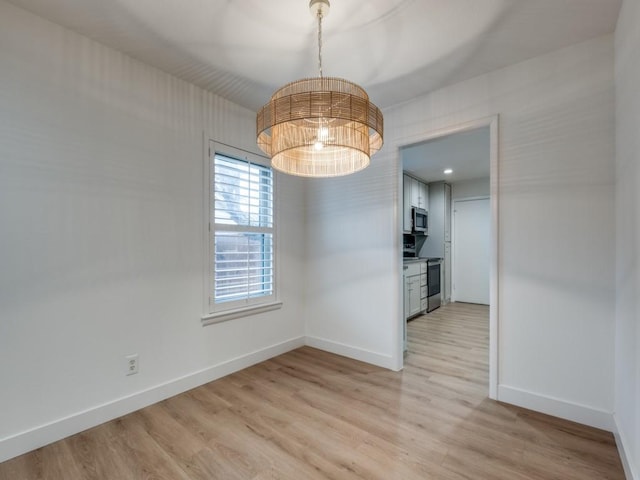 unfurnished dining area with a notable chandelier and light wood-type flooring