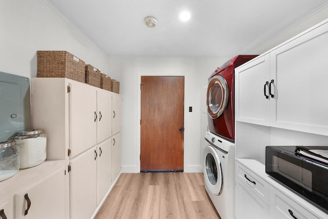 clothes washing area featuring light wood-type flooring, crown molding, and stacked washing maching and dryer