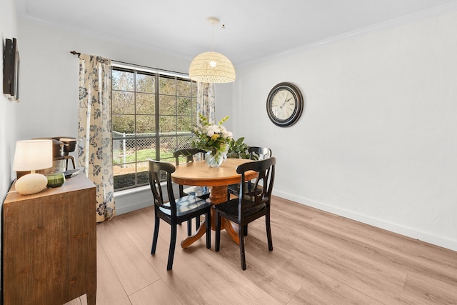 dining space with light hardwood / wood-style floors and ornamental molding