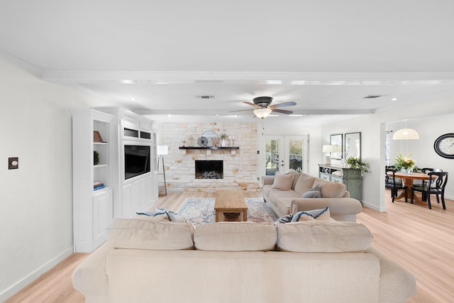 living room featuring light wood-type flooring, beamed ceiling, and a fireplace