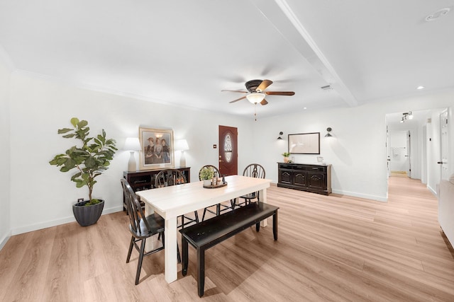 dining space with light wood-type flooring, beamed ceiling, and ceiling fan