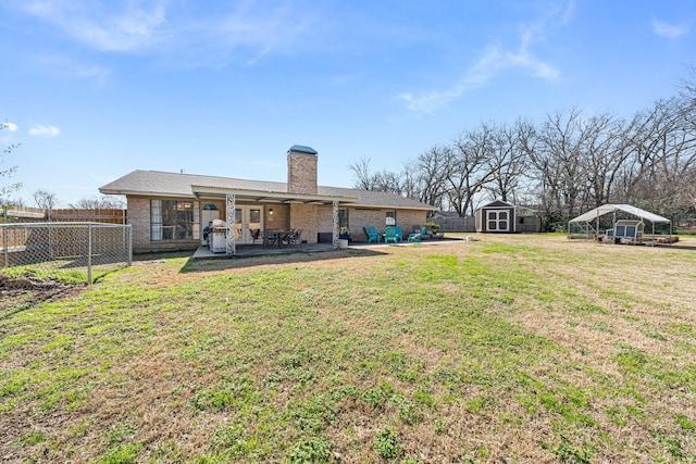 back of house featuring a yard, a patio, and a storage shed