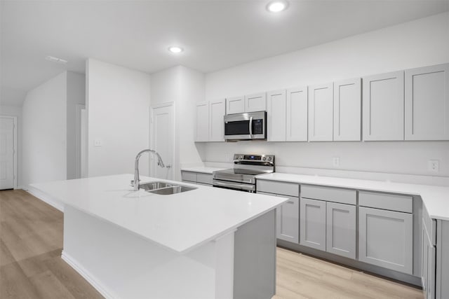 kitchen featuring appliances with stainless steel finishes, light countertops, a sink, and an island with sink