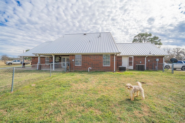 rear view of property with a yard and central AC