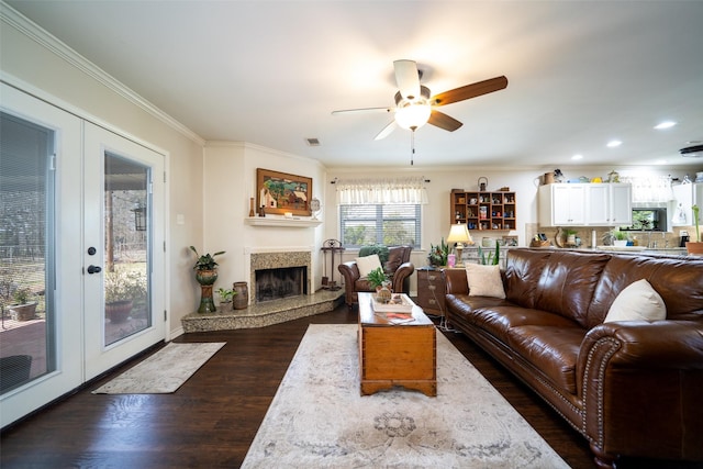 living room with ceiling fan, dark hardwood / wood-style flooring, a fireplace, french doors, and ornamental molding