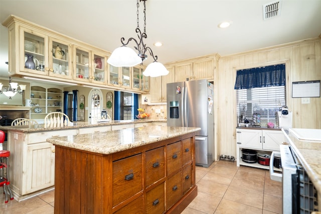 kitchen featuring decorative light fixtures, a center island, light tile patterned floors, stainless steel fridge with ice dispenser, and kitchen peninsula