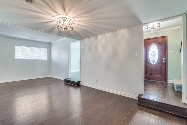 entrance foyer with ornamental molding, a chandelier, and dark hardwood / wood-style floors