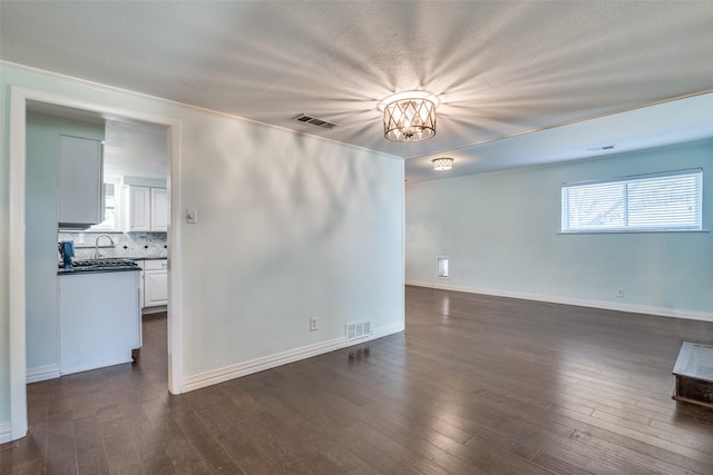 spare room featuring a notable chandelier, a textured ceiling, sink, and dark hardwood / wood-style floors