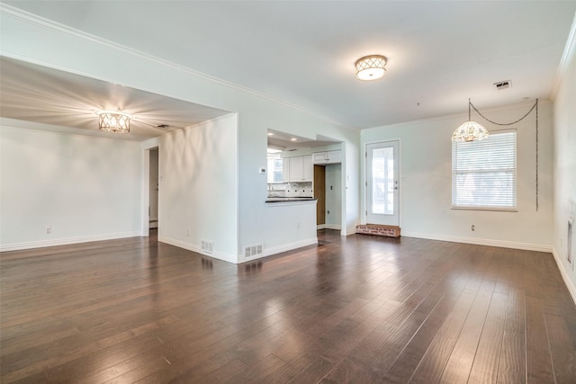 unfurnished living room with dark hardwood / wood-style flooring, a notable chandelier, and ornamental molding